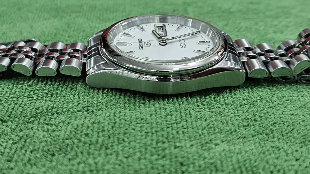 A watch with a white dial and jubilee bracelet after service